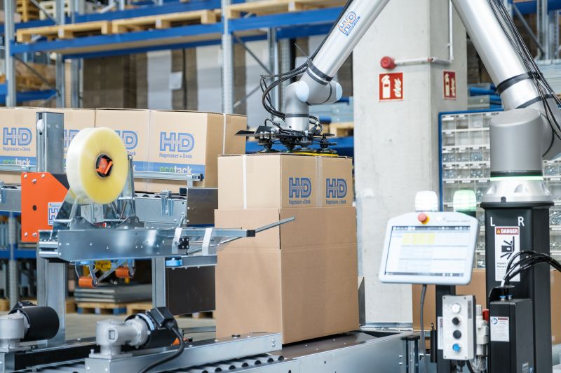 Cobot befüllt aufgerichteten Karton